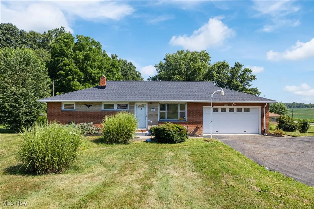 Ranch-style home with driveway, brick siding, a front lawn, and an attached garage