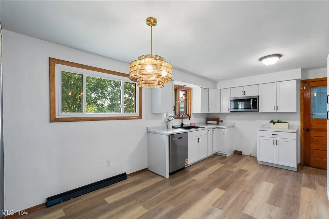 Kitchen featuring white cabinetry, stainless steel appliances, light countertops, and light wood-type flooring