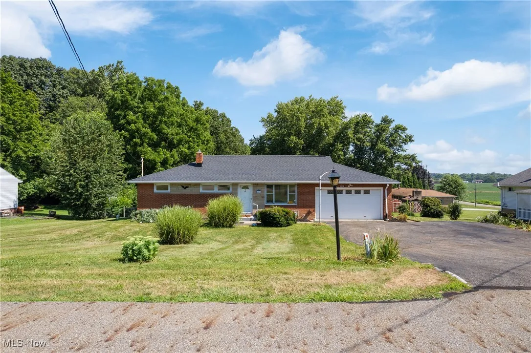 Single story home featuring driveway, a garage, a front yard, and brick siding