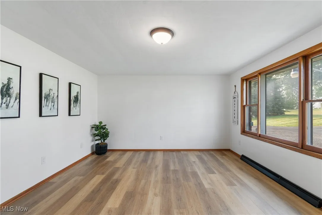 Unfurnished room with light wood-style flooring and a baseboard radiator