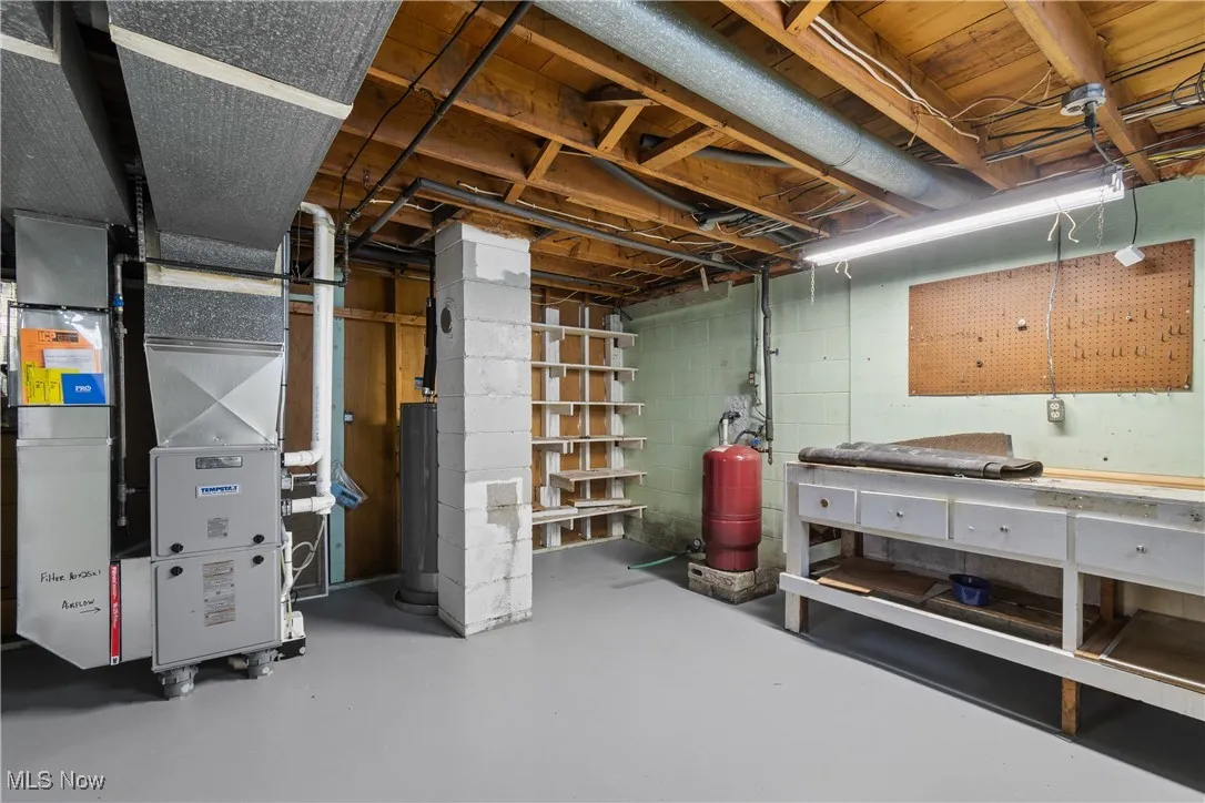 Unfinished basement featuring a workshop area, water heater, and heating unit