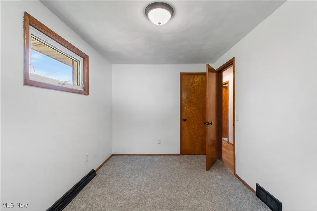 Empty room with light carpet and baseboards