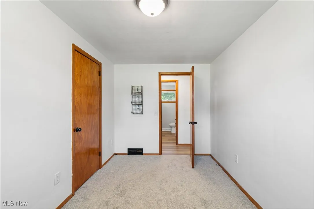 Unfurnished bedroom featuring light carpet and baseboards