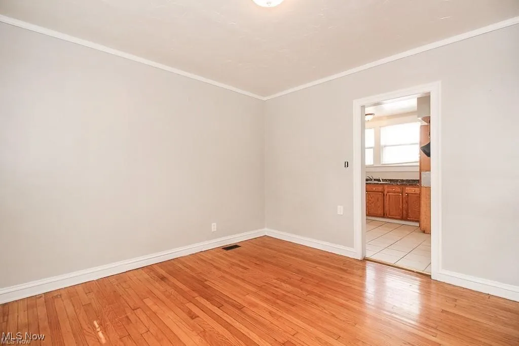 Empty room with ornamental molding and light wood-style floors