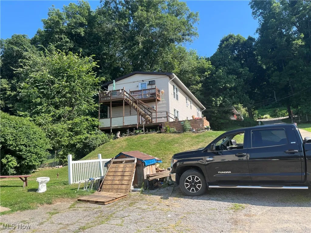 View of front of home with stairs and a wooden deck
