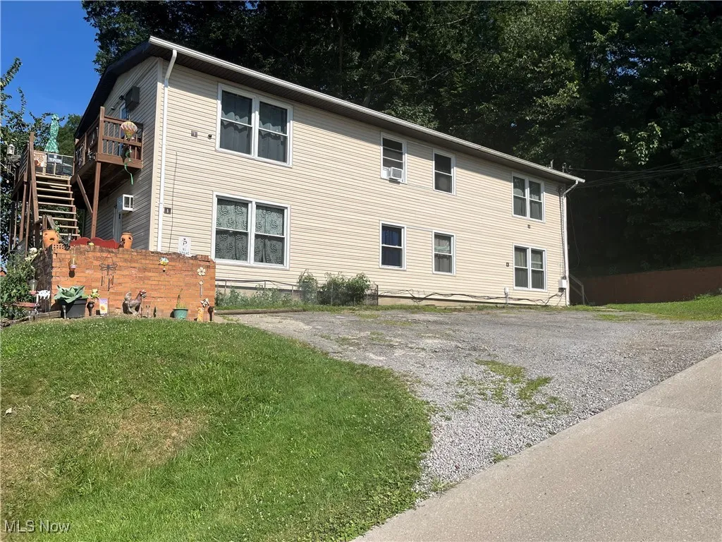 View of front of house featuring stairway, a front lawn, and a wooden deck