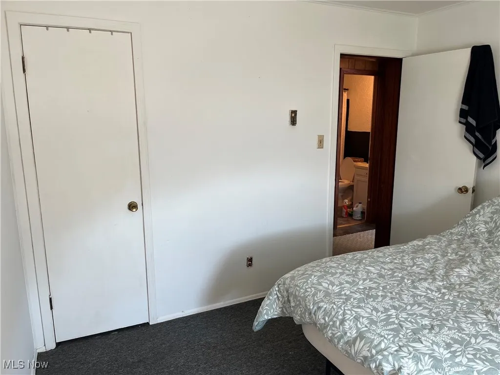 Bedroom with dark colored carpet and baseboards
