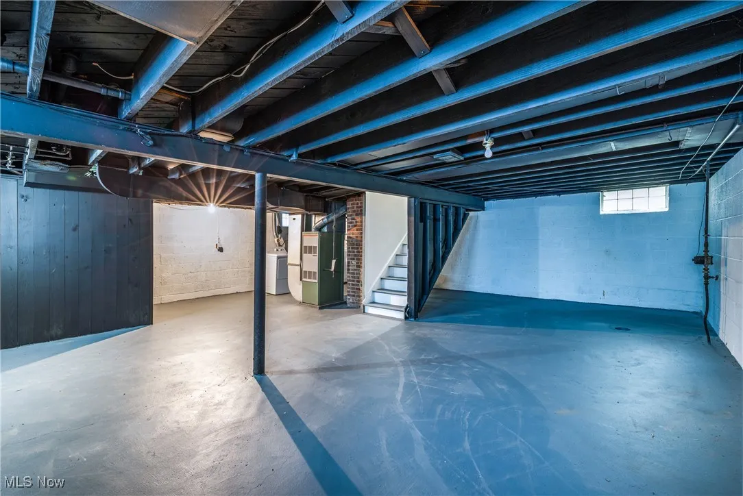 Below grade area featuring stairway, washer / dryer, and heating unit