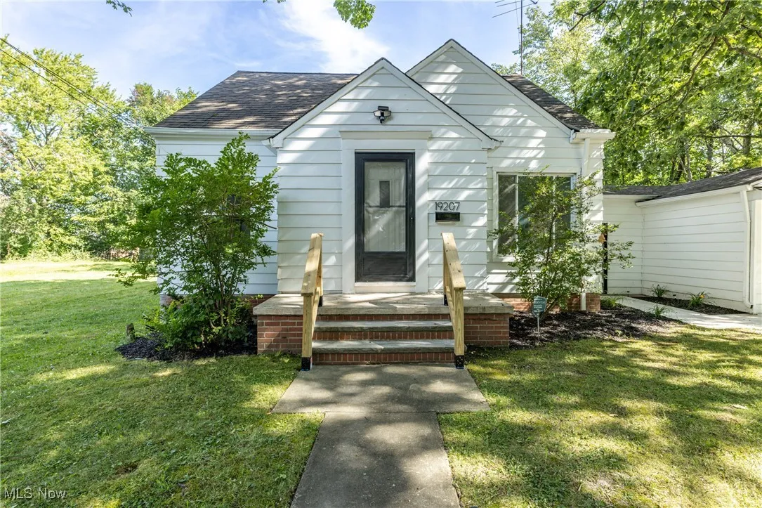 View of front of house with a front lawn and roof with shingles