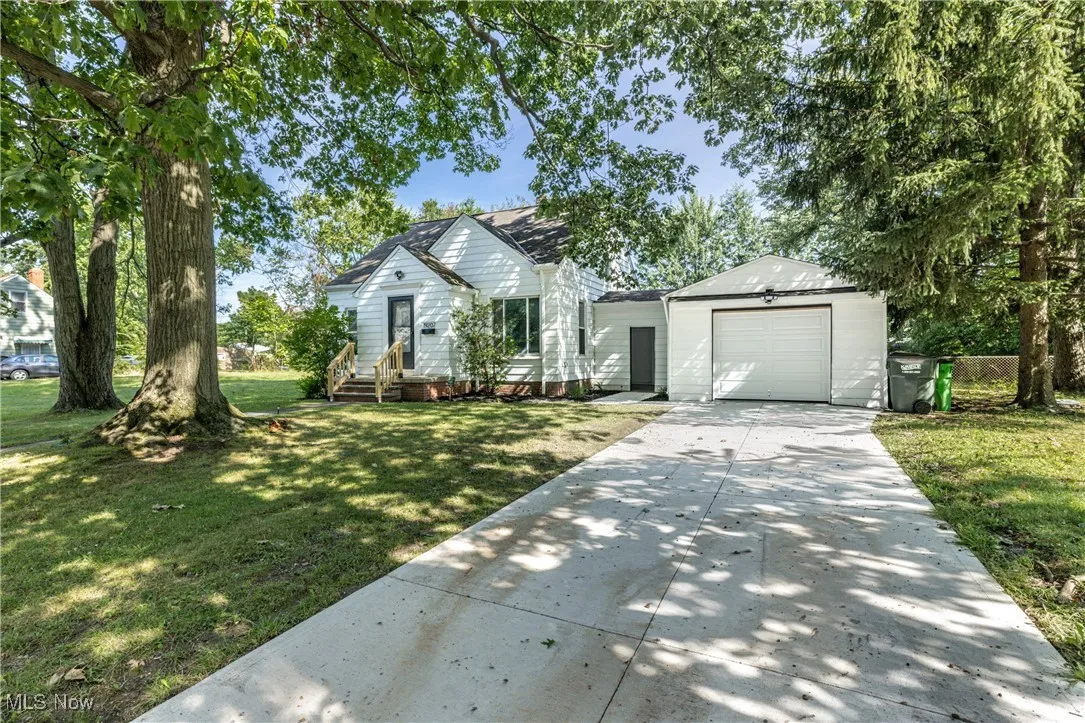 View of front of home featuring concrete driveway, a front lawn, and an attached garage