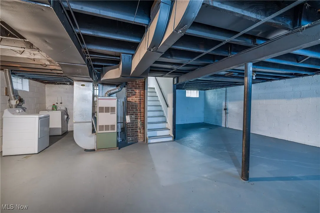 Below grade area featuring washer and dryer, stairs, and heating unit