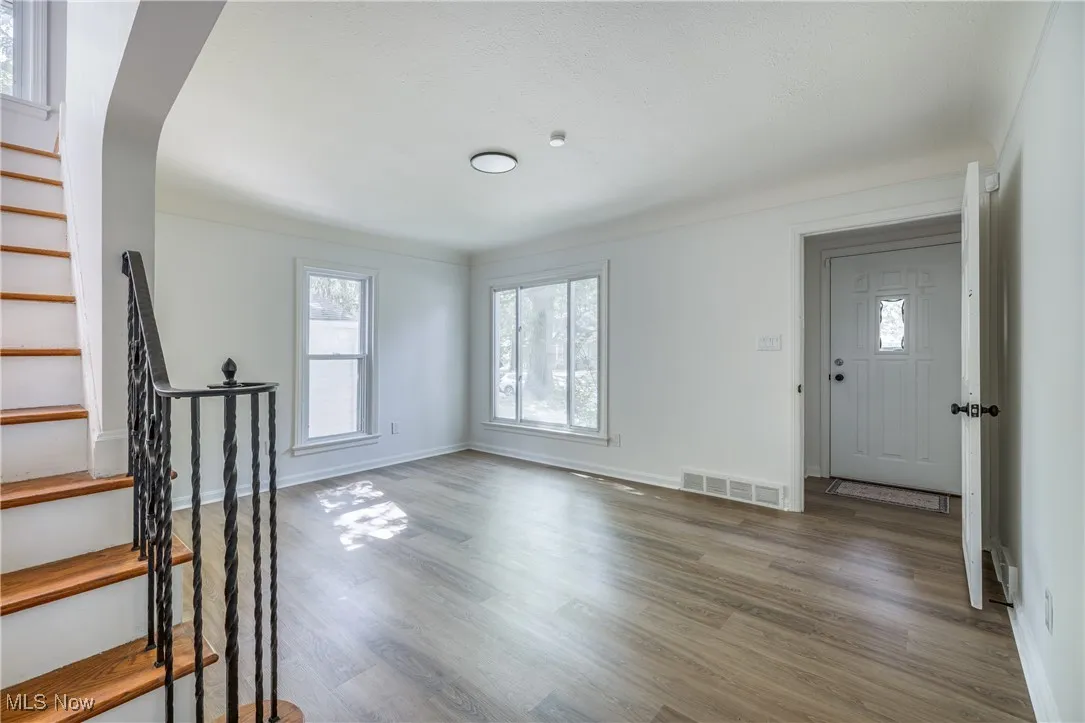 Foyer entrance with wood finished floors, stairway, and arched walkways