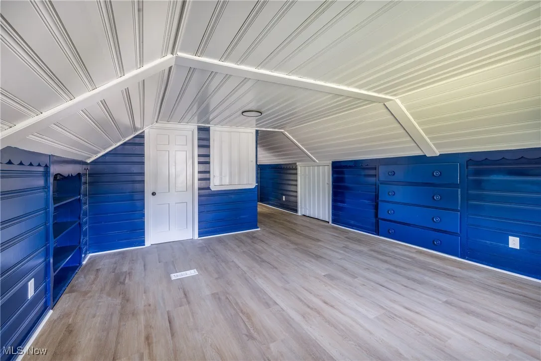 Additional living space featuring wood finished floors, wood walls, and lofted ceiling