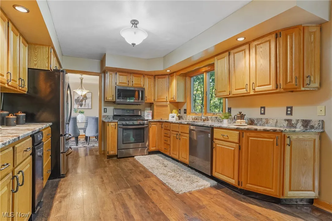 Kitchen featuring recessed lighting, dark wood-type flooring, appliances with stainless steel finishes, and light stone countertops