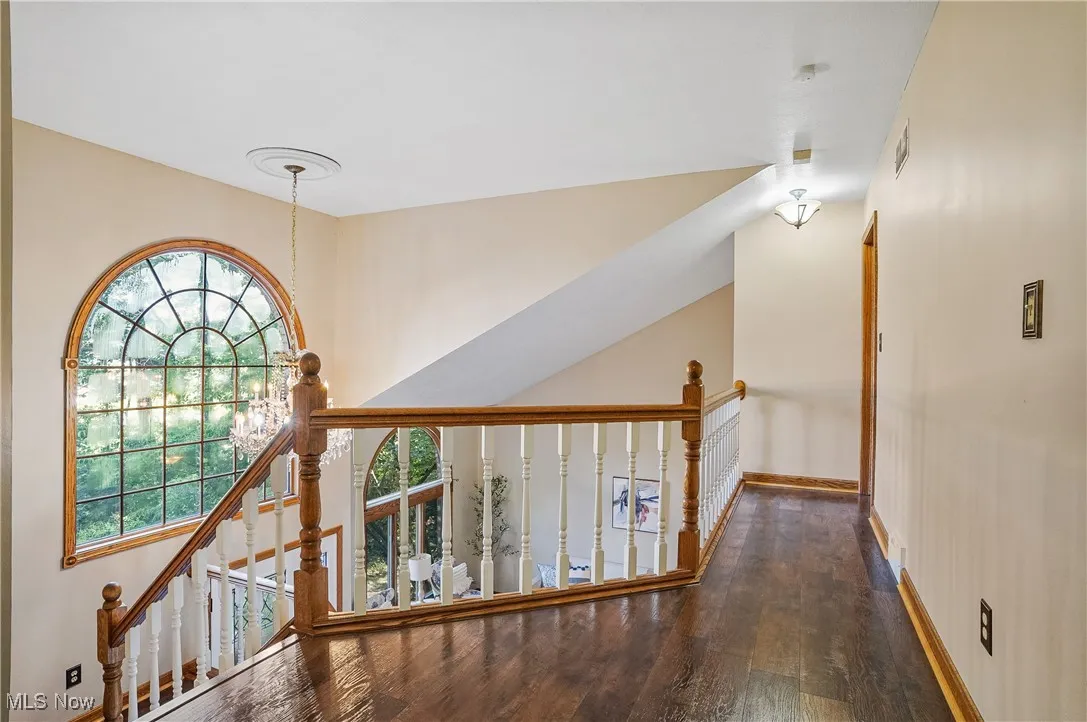 Hallway with wood finished floors and an upstairs landing
