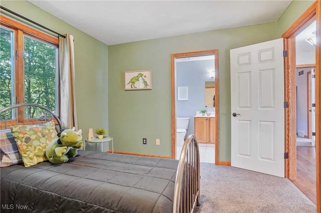 Carpeted bedroom featuring connected bathroom and baseboards
