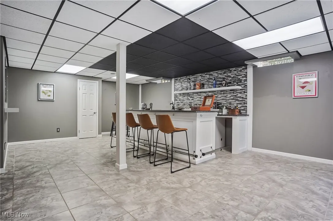 Indoor wet bar with a paneled ceiling and baseboards