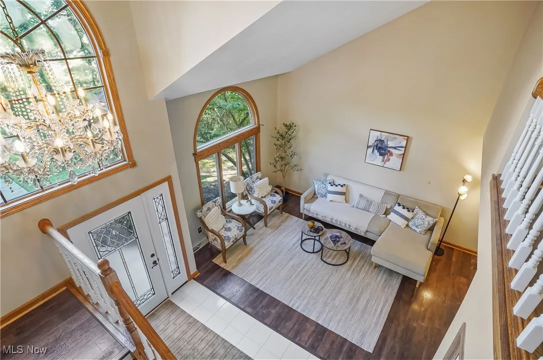 Living area featuring high vaulted ceiling, wood finished floors, stairway, and a chandelier