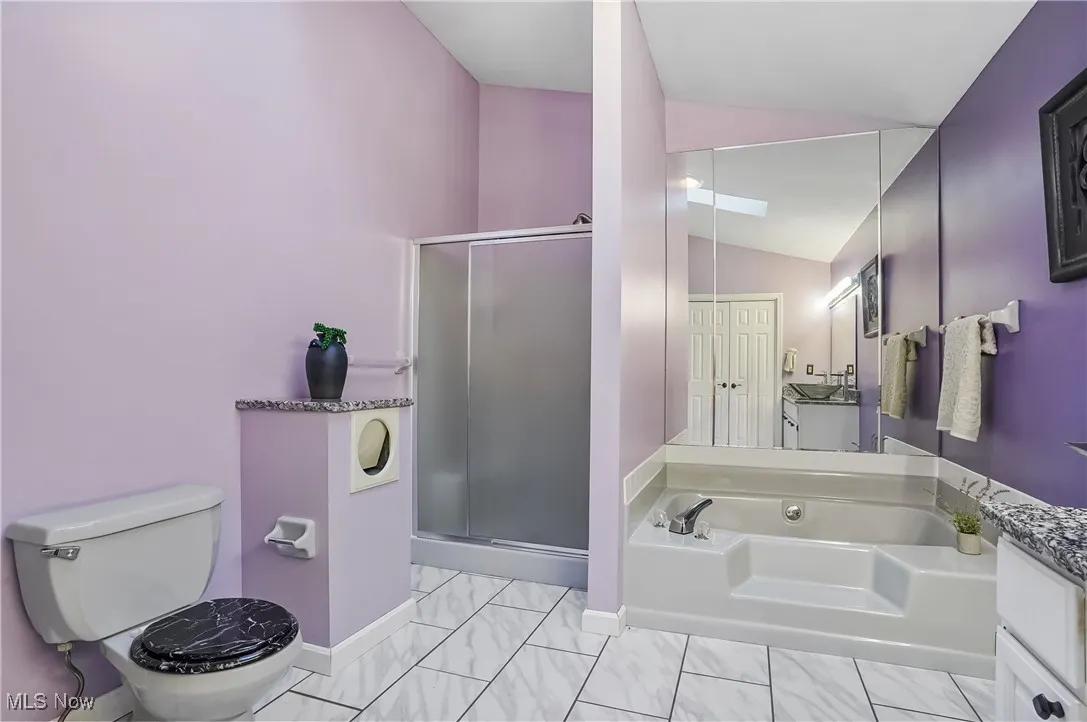 Full bath with vaulted ceiling, vanity, a shower stall, and a bath