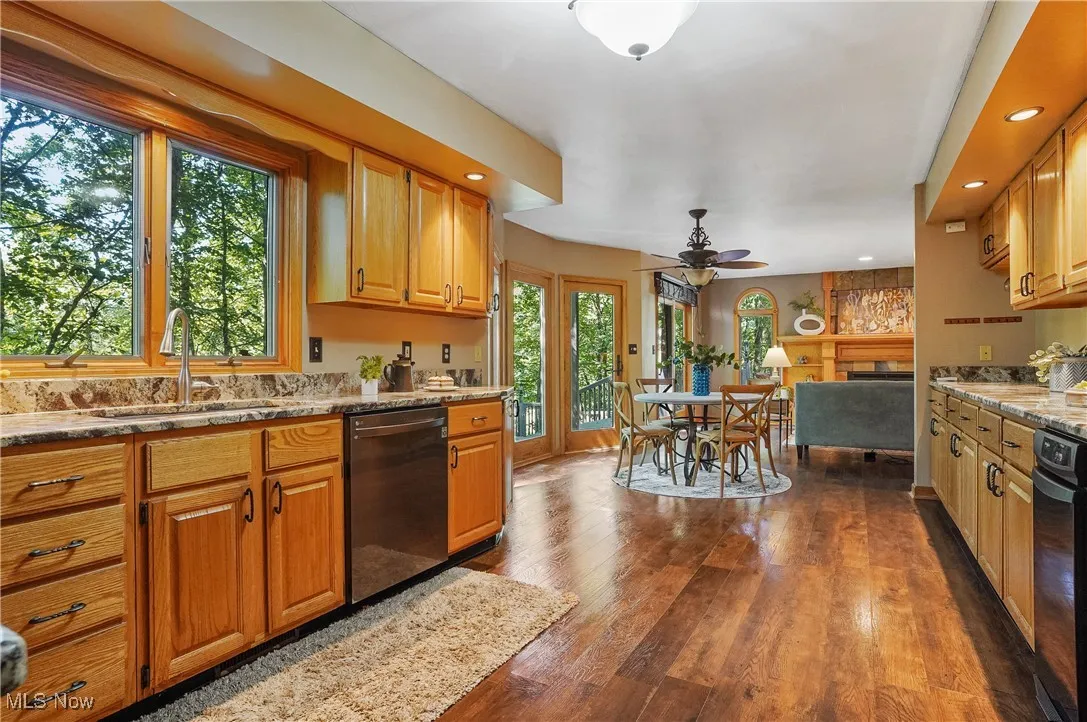 Kitchen featuring recessed lighting, black dishwasher, a ceiling fan, dark wood-style floors, and light stone countertops