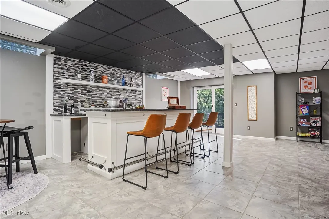 Indoor wet bar with a drop ceiling and backsplash
