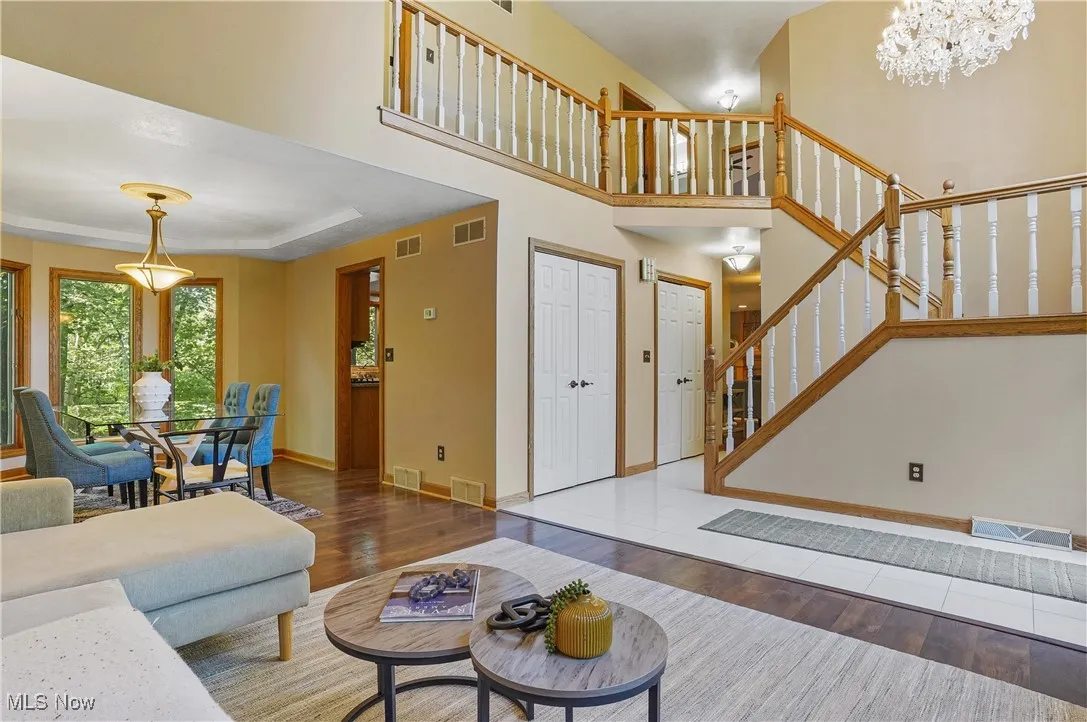 Living area featuring wood finished floors, stairway, a high ceiling, and a chandelier
