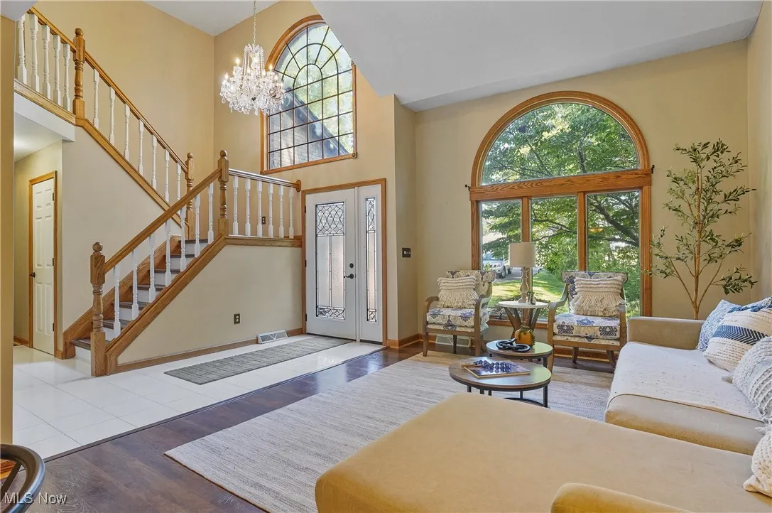 Living area featuring a chandelier, wood finished floors, stairway, and a high ceiling