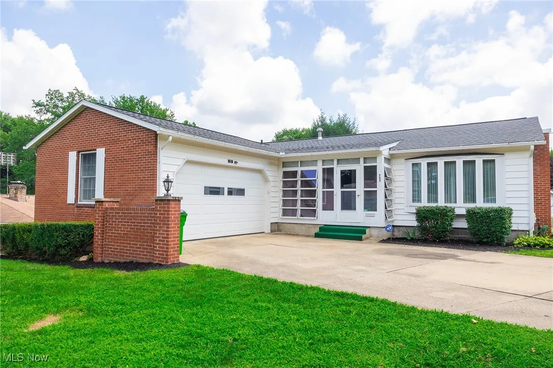 View of front of property with concrete driveway, an attached garage, a front yard, and a shingled roof