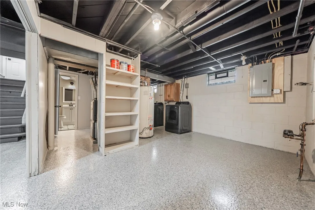 Basement with washer and dryer, water heater, electric panel, and stairs