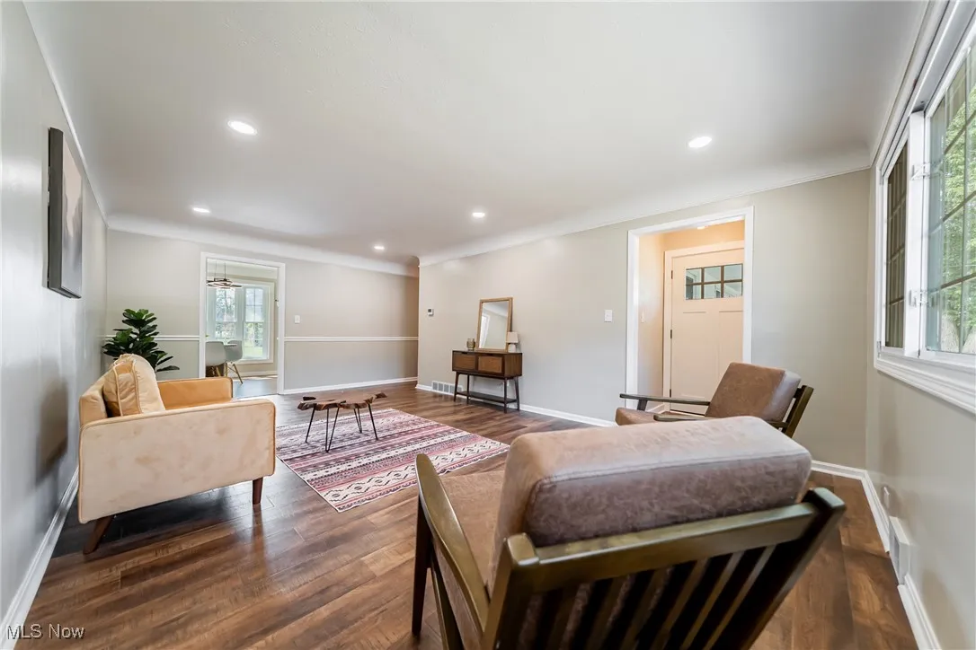 Living area with dark wood-style floors, ornamental molding, and recessed lighting