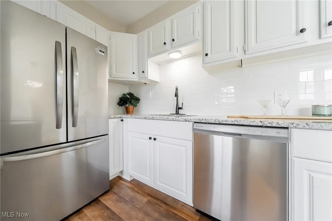Kitchen featuring stainless steel appliances, dark wood-style flooring, and white cabinets