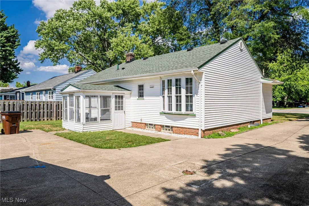 Rear view of property featuring a sunroom, a shingled roof, and a chimney
