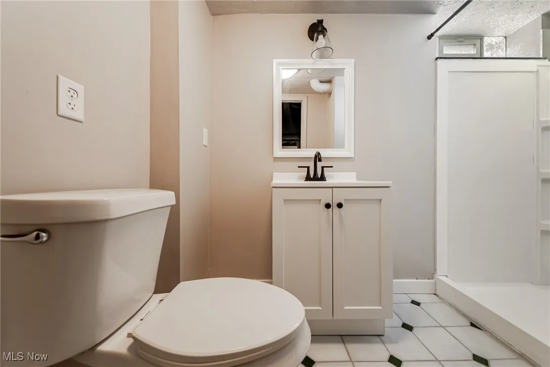 Half bathroom featuring vanity, tile patterned flooring, and a textured ceiling