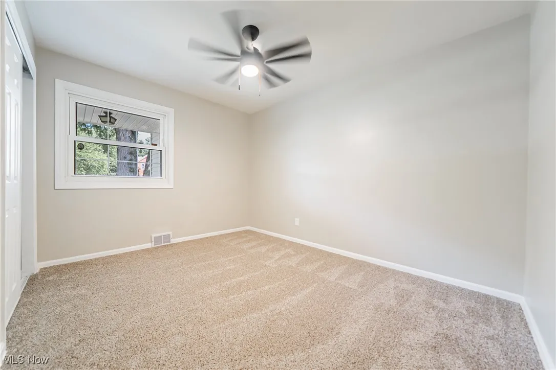 Carpeted empty room with baseboards and a ceiling fan