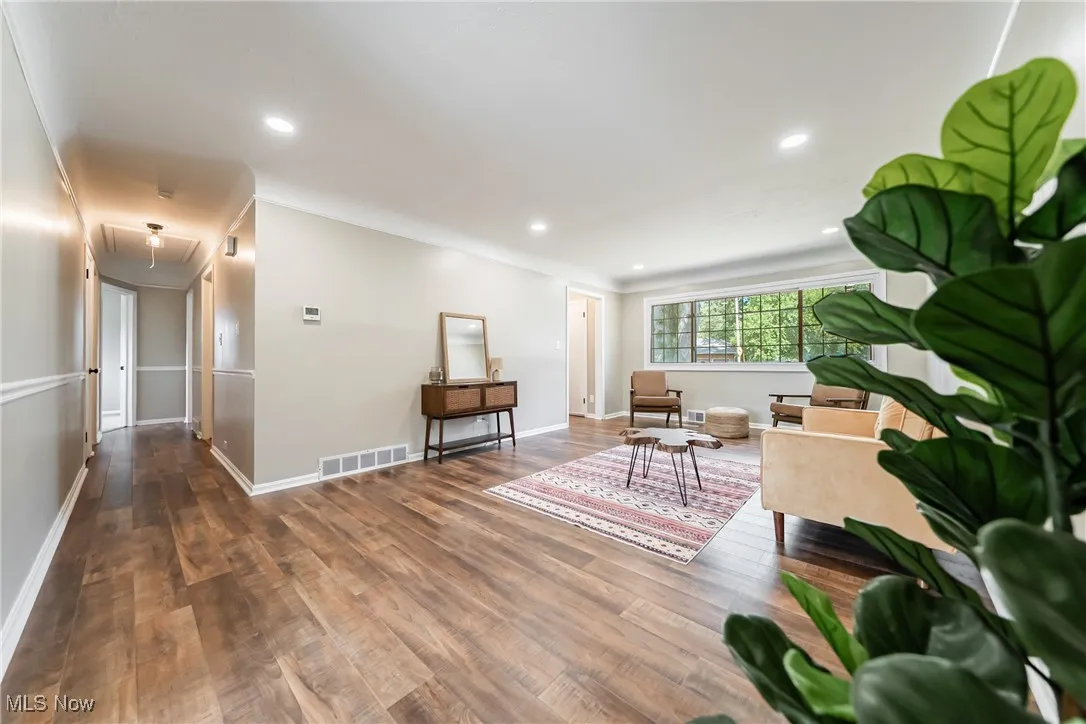 Living area with attic access, wood finished floors, recessed lighting, and ornamental molding