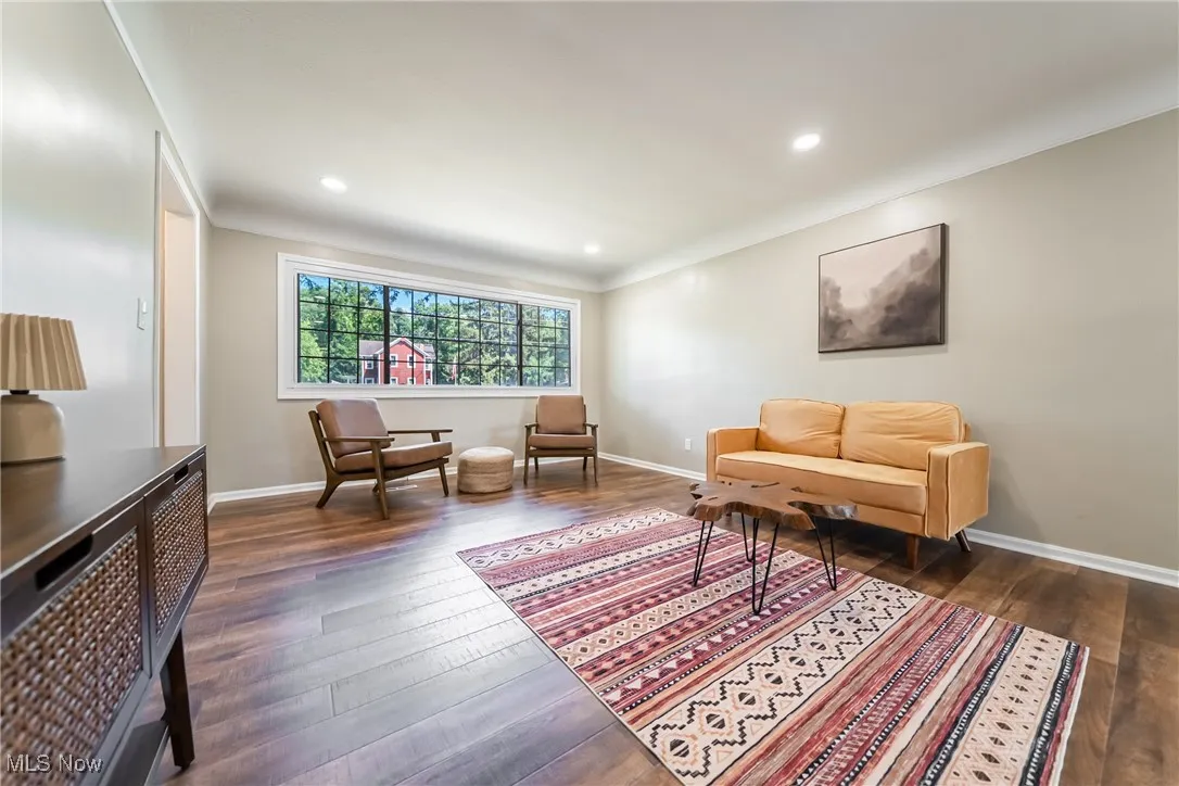 Living area with dark wood-type flooring, ornamental molding, and recessed lighting