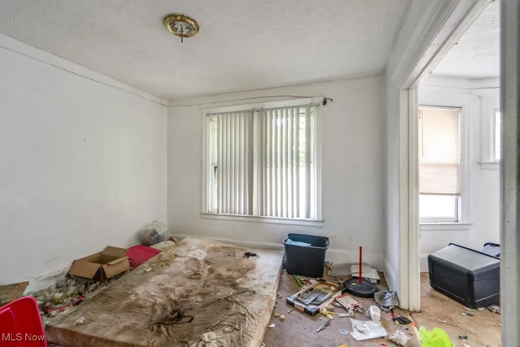 Empty room with a textured ceiling, plenty of natural light, and ornamental molding