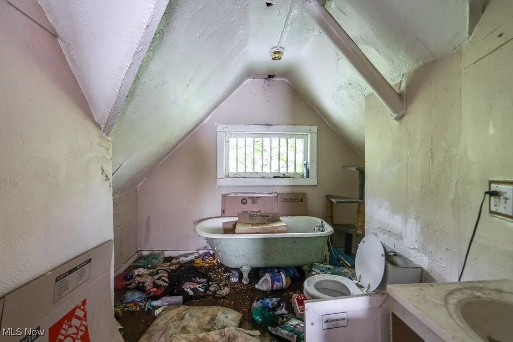 Bathroom with a freestanding tub, lofted ceiling, and vanity