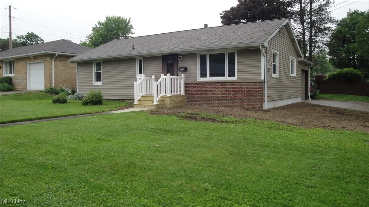 Single story home with brick siding, a front yard, a garage, concrete driveway, and a shingled roof