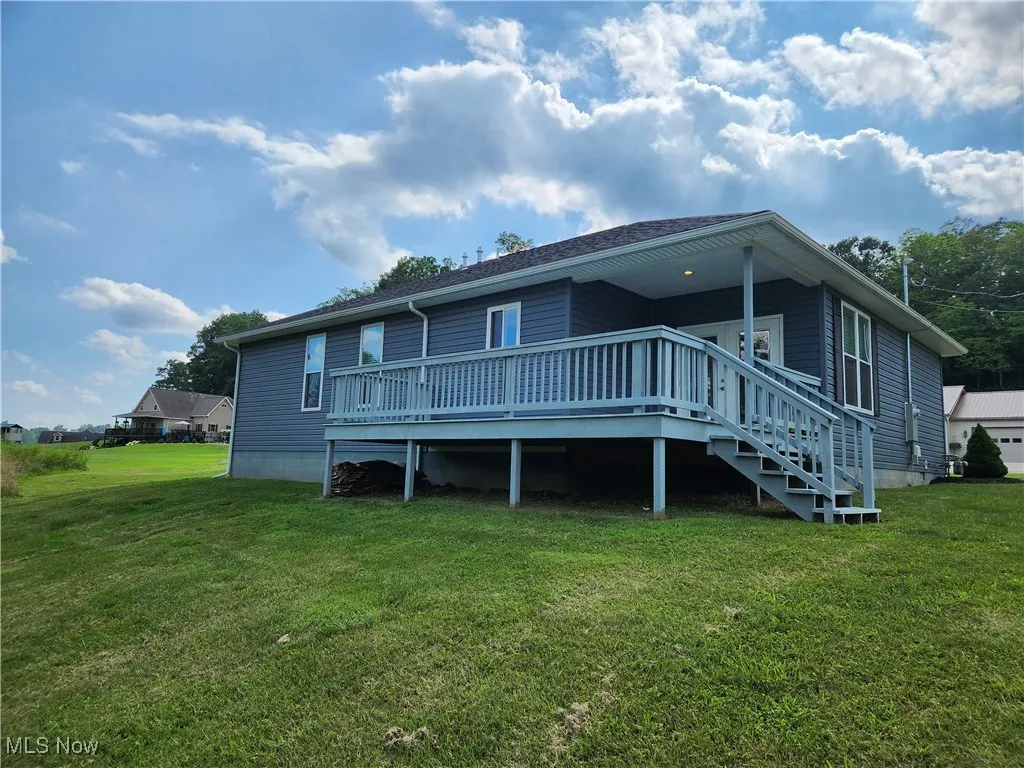 Back of property featuring a wooden deck and a lawn
