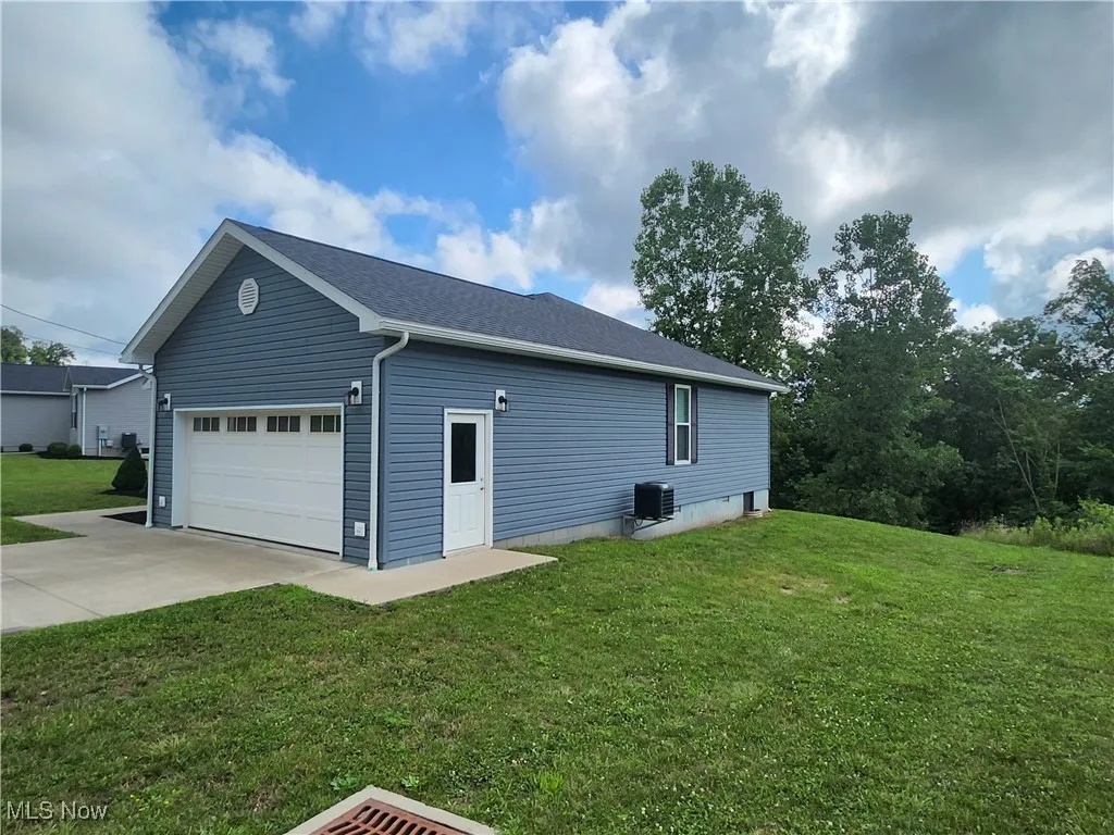 View of property exterior with driveway, a yard, and a garage