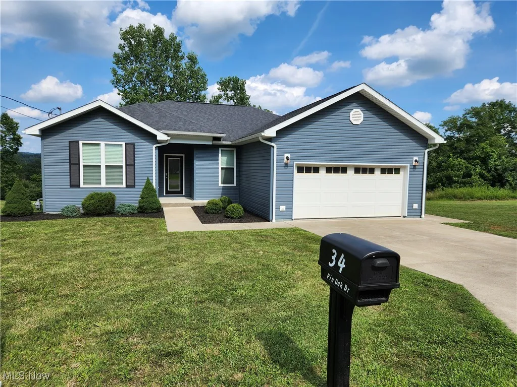 Ranch-style home with concrete driveway, an attached garage, a front lawn, and a shingled roof