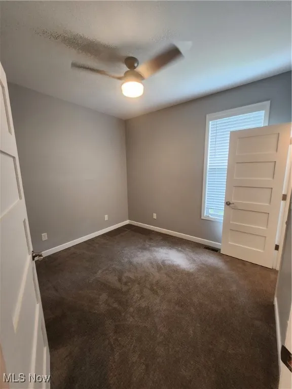 Bedroom featuring dark colored carpet, ceiling fan, and a textured ceiling