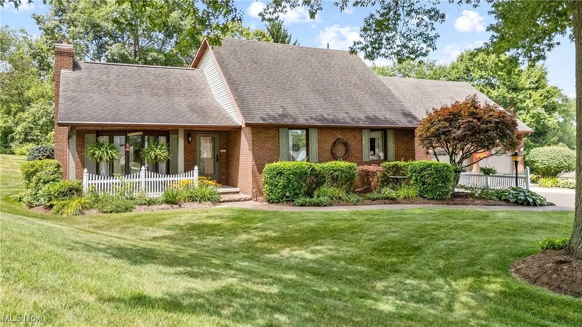 View of front of house featuring a chimney, a front yard, a shingled roof, and brick siding