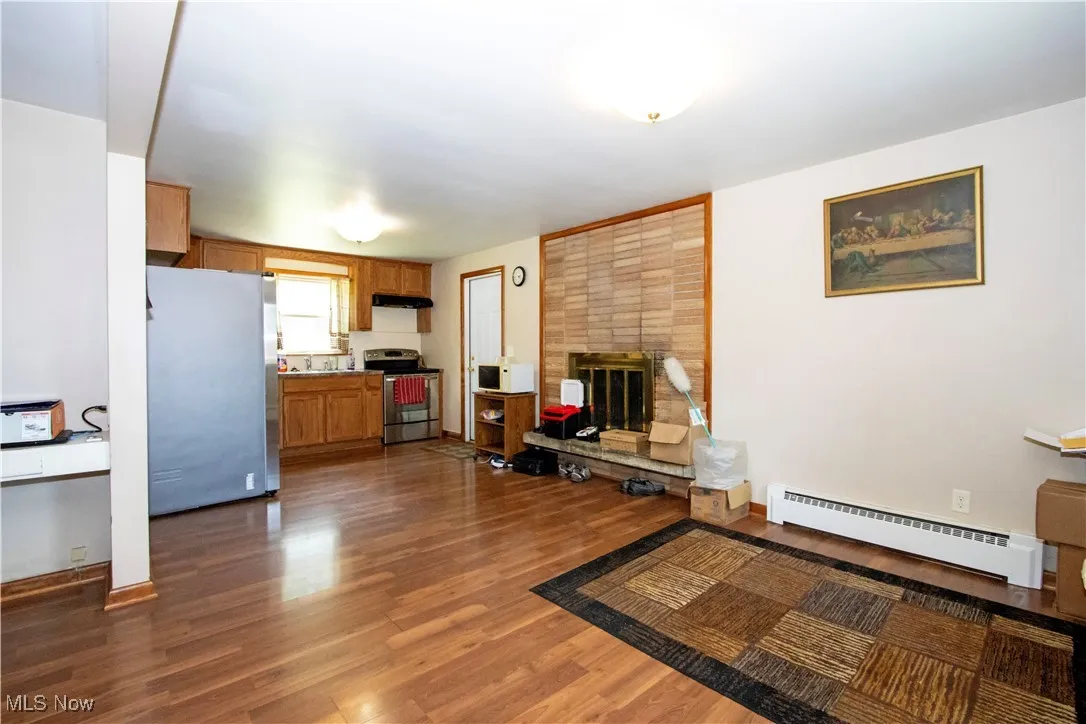 Living room featuring a baseboard radiator, wood finished floors, and a fireplace