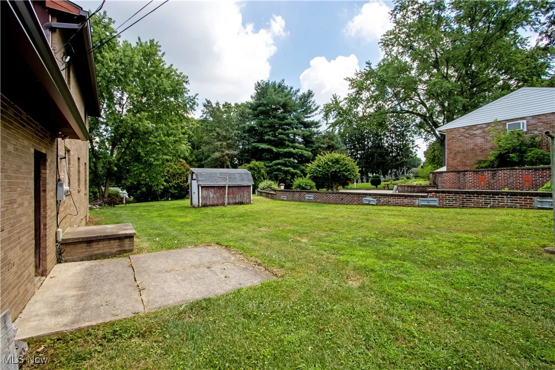 View of grassy yard featuring a storage shed and view of scattered trees