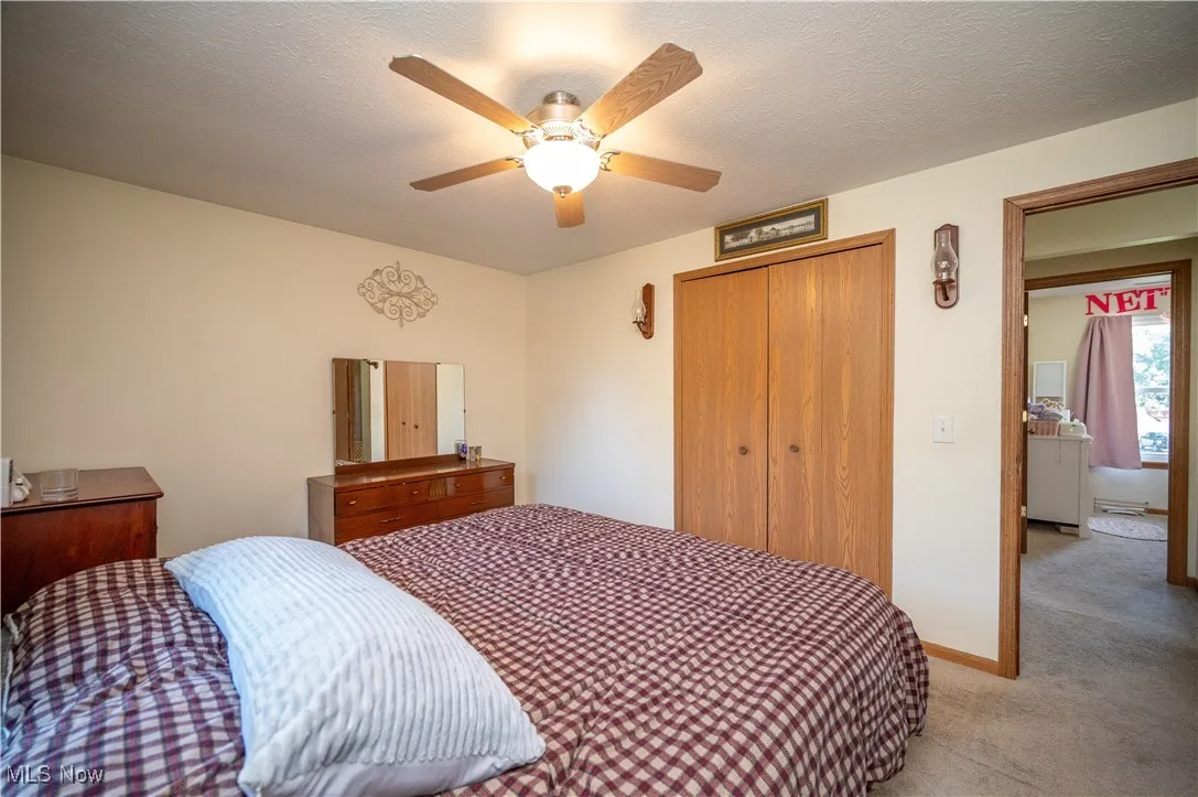 Carpeted bedroom with a closet, a textured ceiling, and ceiling fan