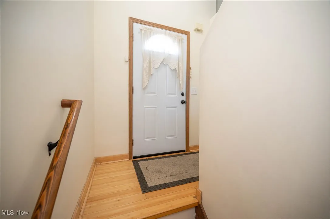 Doorway to outside with wood finished floors and baseboards