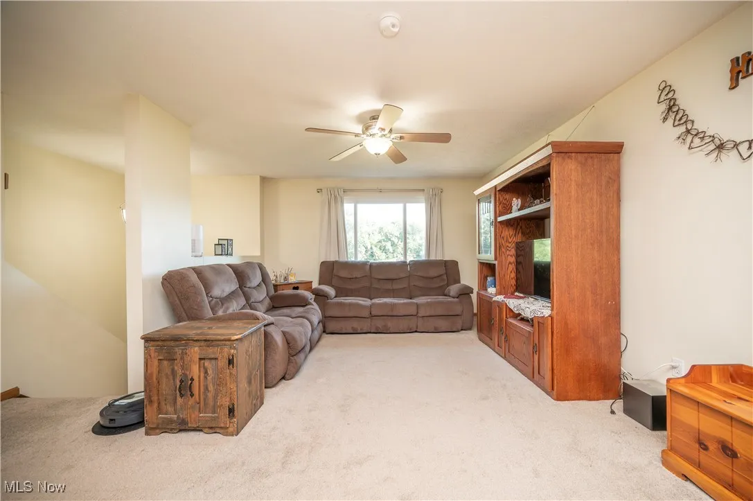 Living area with light carpet and ceiling fan
