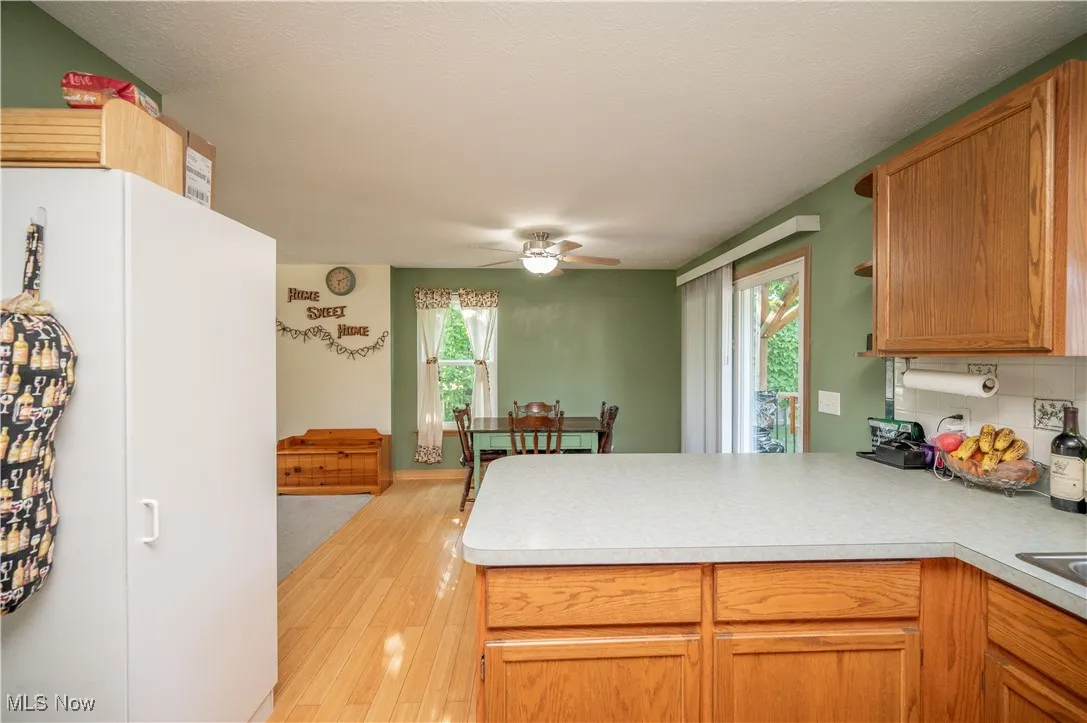 Kitchen featuring a peninsula, backsplash, light wood-style flooring, and light countertops